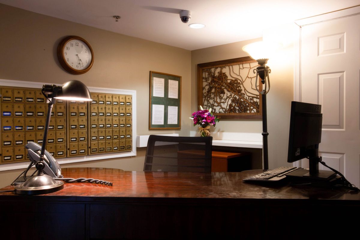 A warmly lit reception area with a desk, lamp, computer, and decorative elements.