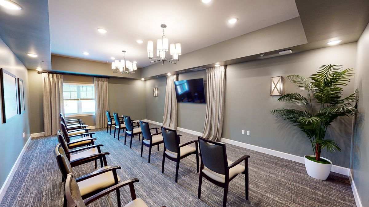 A modern conference room setup with arranged chairs and a TV screen on the wall.