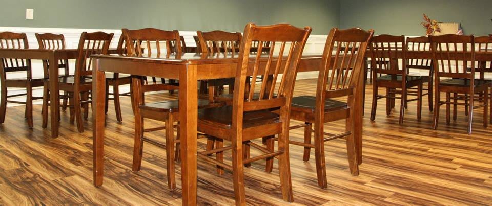 A wooden dining table set with multiple chairs in a well-lit dining room.