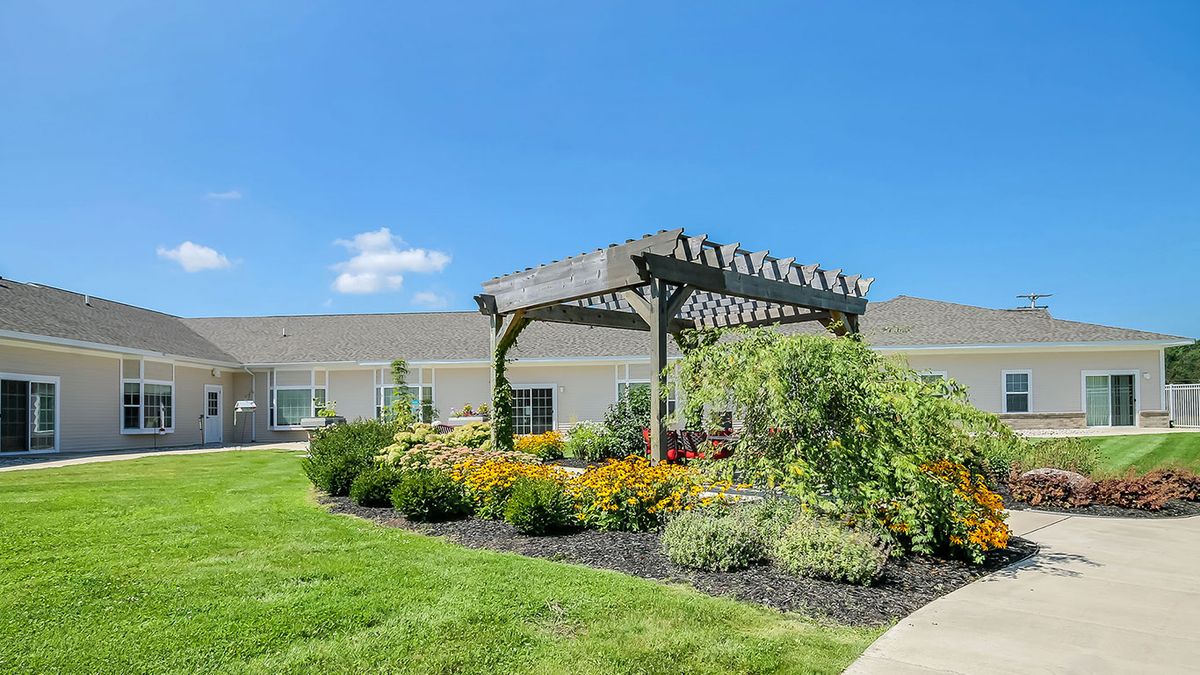 A beautifully landscaped garden with a wooden pergola under a clear blue sky.