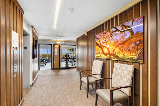A modern hallway featuring wooden paneling and artwork, complemented by comfortable seating.