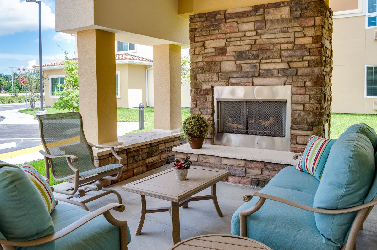 A cozy outdoor patio with comfortable seating and a stone fireplace.
