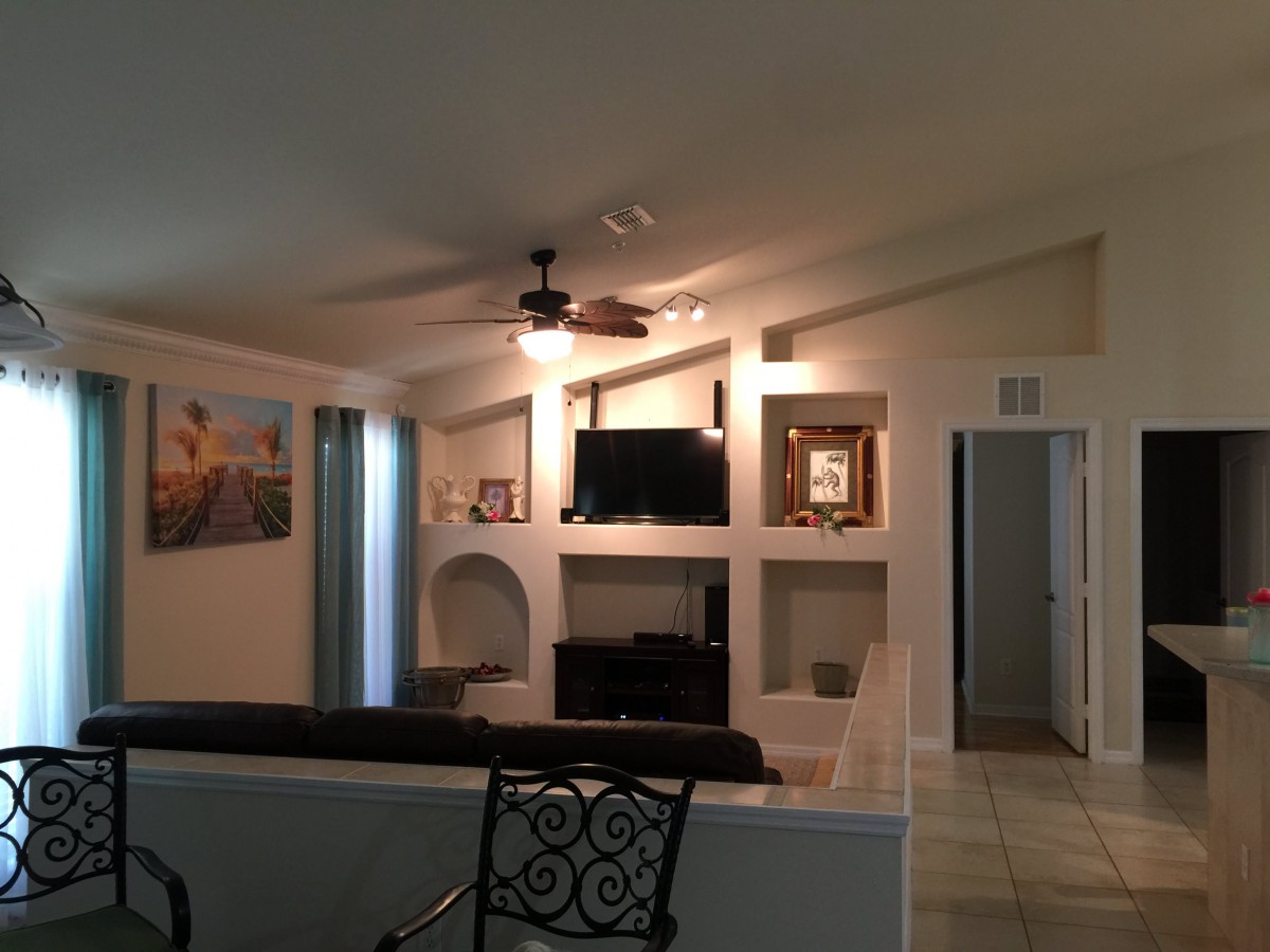 A cozy living room featuring a television, sofa, ceiling fan, and decorative elements.
