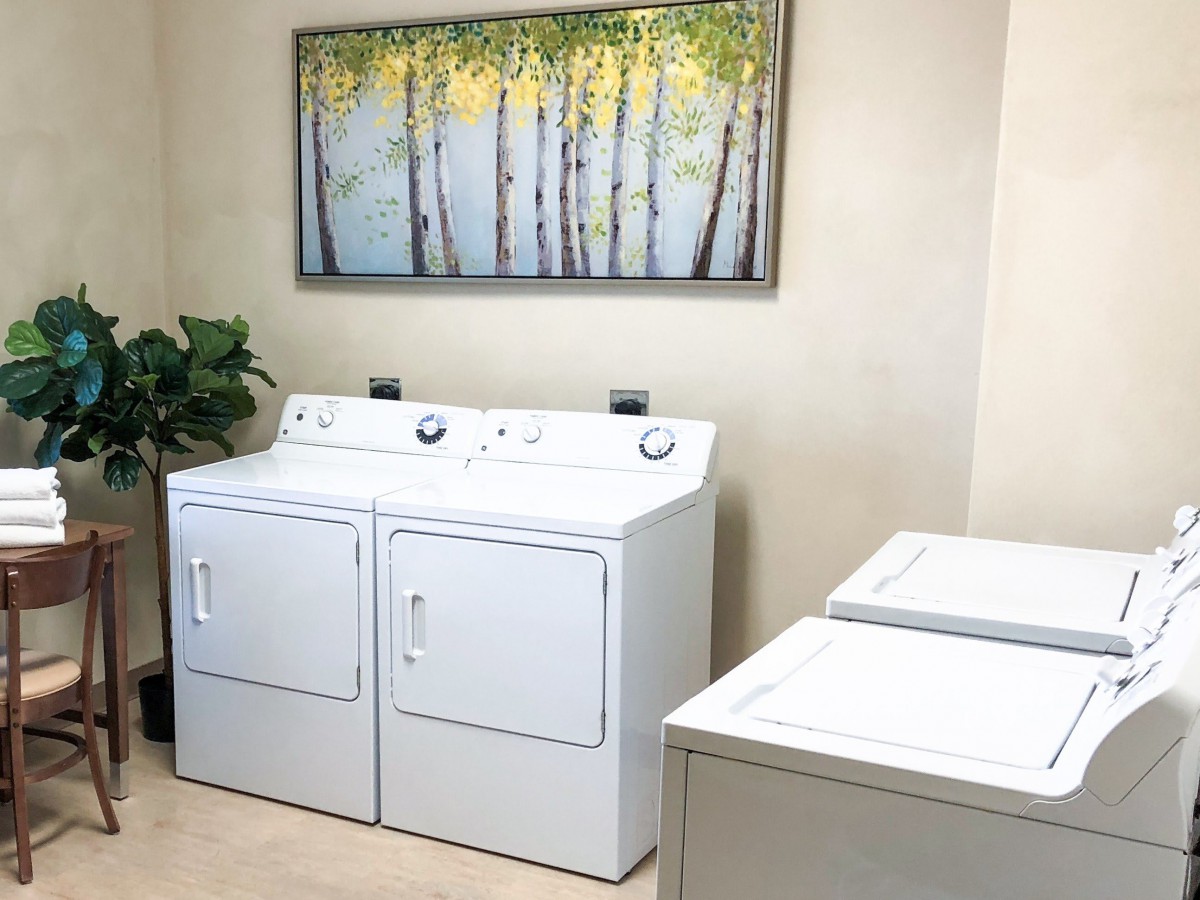 A neatly organized laundry room with a washing machine, dryer, and wall decor.