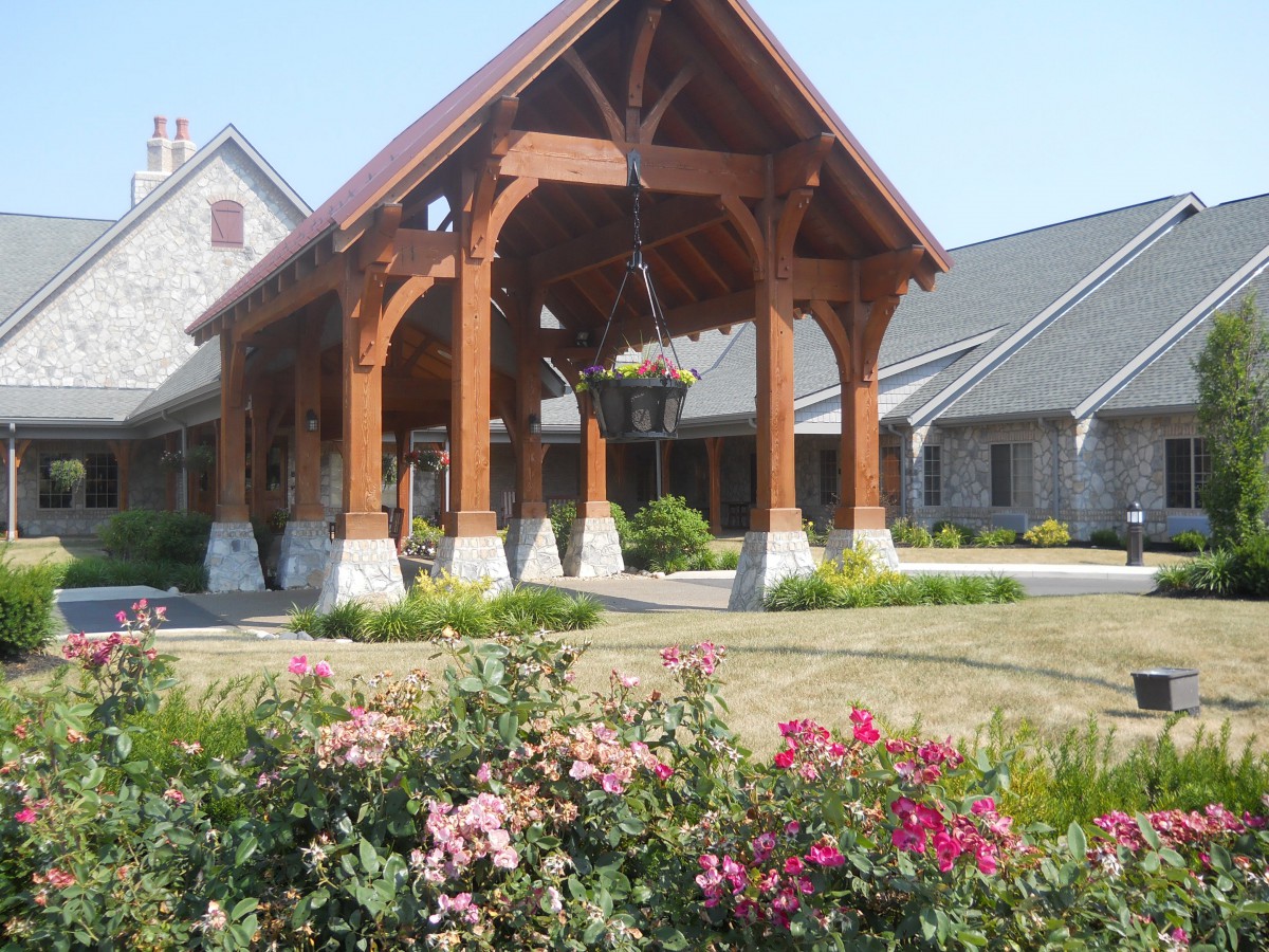 A picturesque building featuring a wooden entrance, surrounded by a well-maintained garden with colorful flowers.