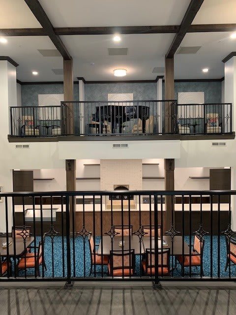 A modern hotel lobby with a seating area and upper-level balcony.