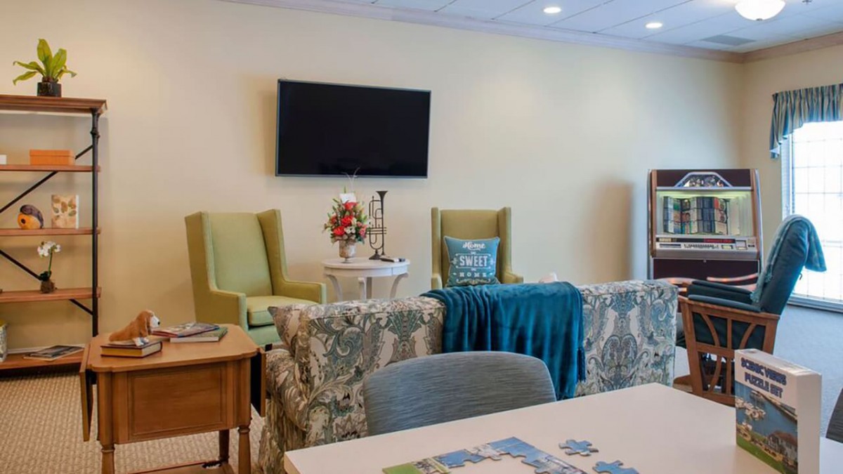A cozy living room with a television, comfortable chairs, and decorative elements.