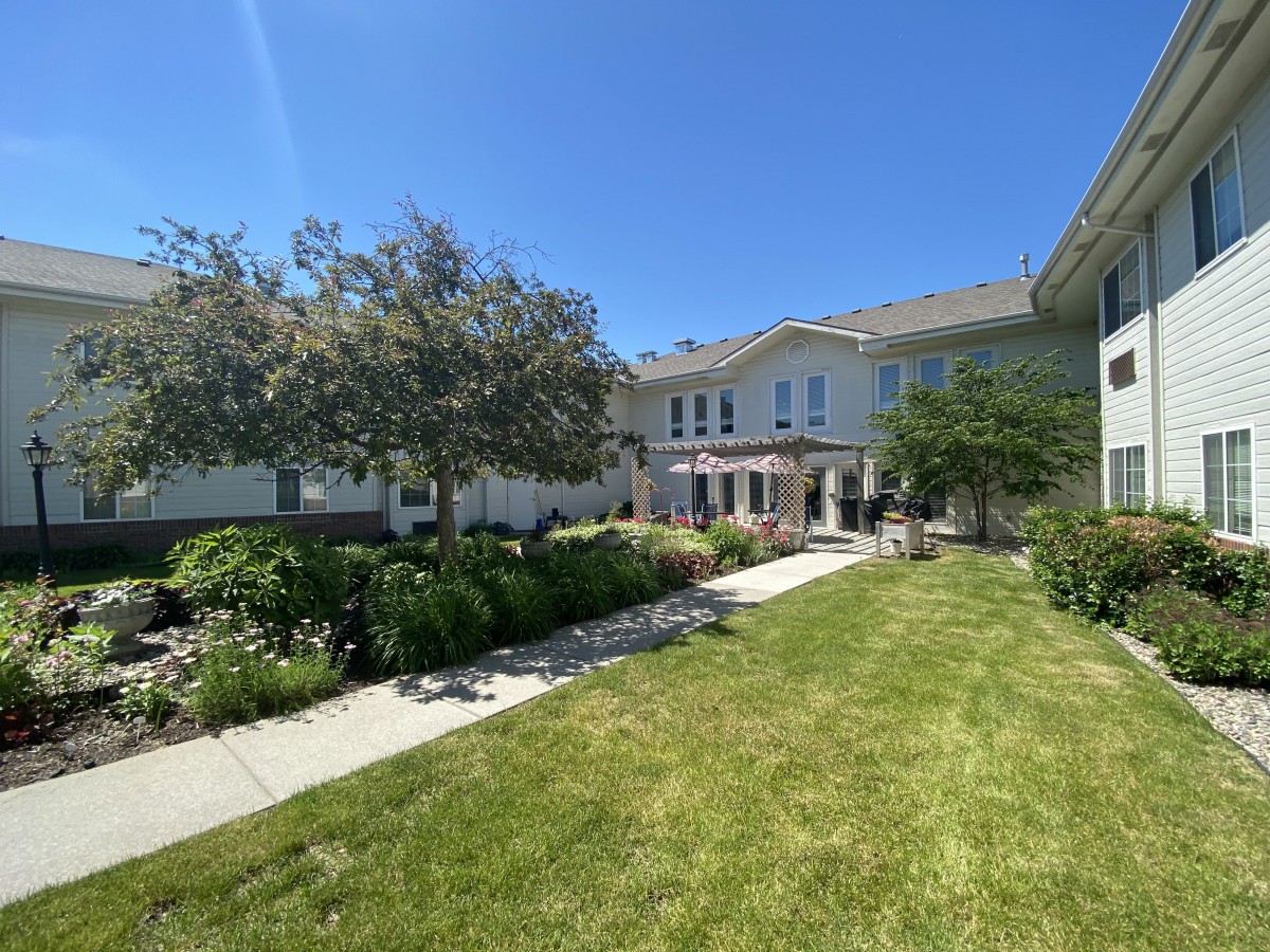 A view of a house with a well-maintained lawn and garden on a sunny day.