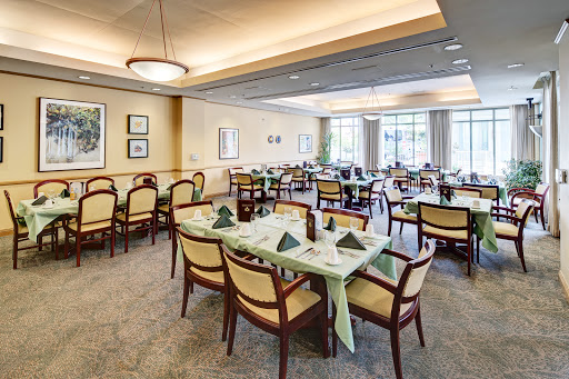 A well-lit dining room set up with neatly arranged tables and chairs, featuring green decorative elements.