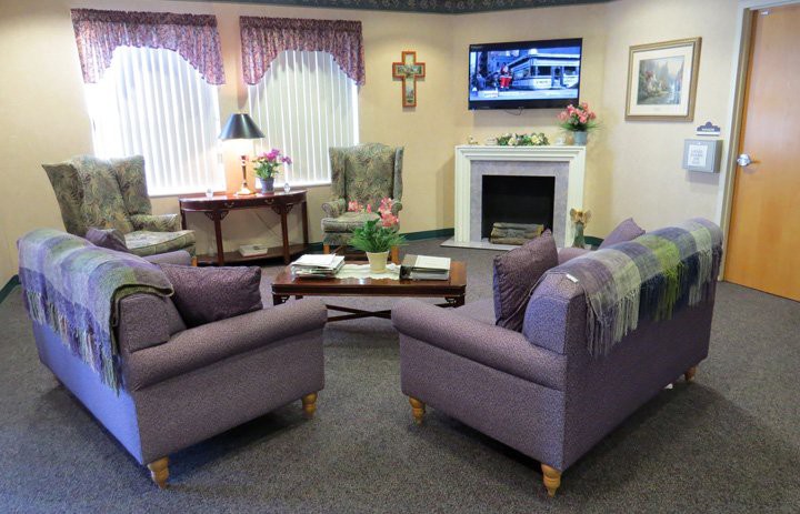 A cozy living room with purple sofas and a fireplace, featuring a television and tasteful decor.