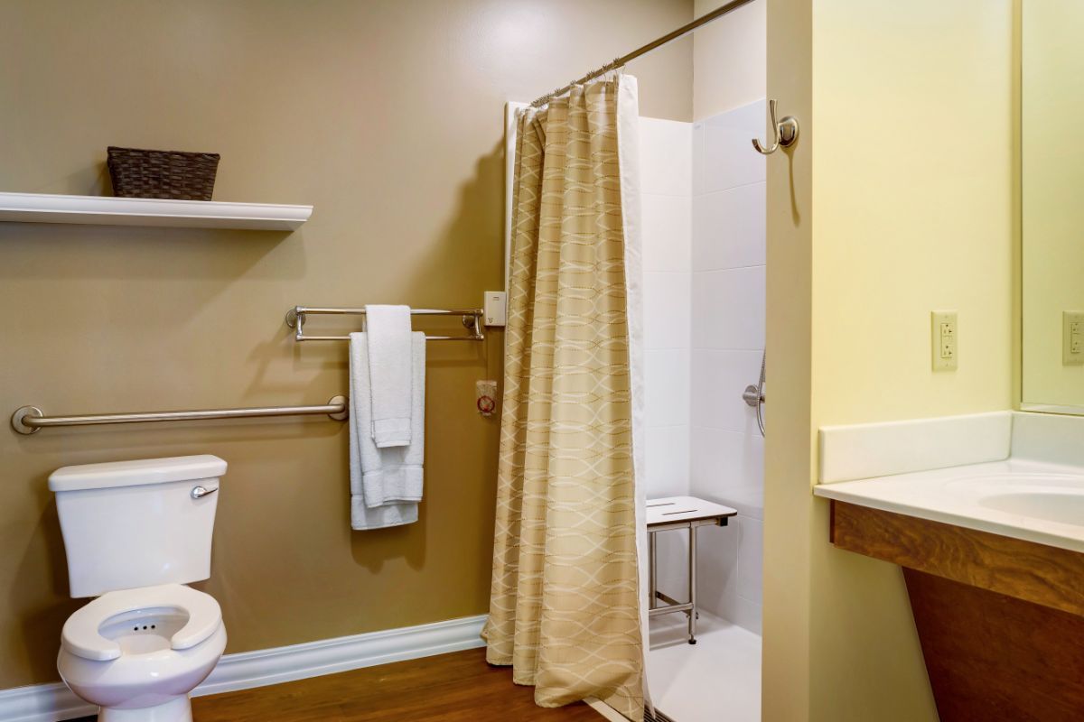 An accessible bathroom with a shower curtain, grab bars, and towels neatly arranged on a towel rack.