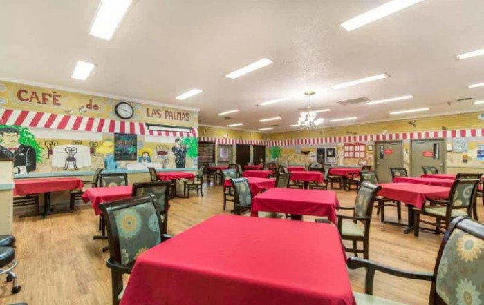 An empty dining area with red tablecloths and decorated walls.