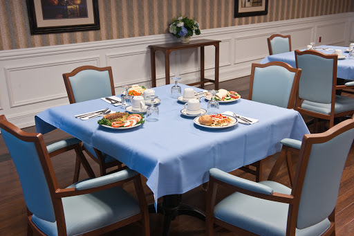 A neatly arranged dining table with a blue tablecloth, featuring plates of food and utensils.