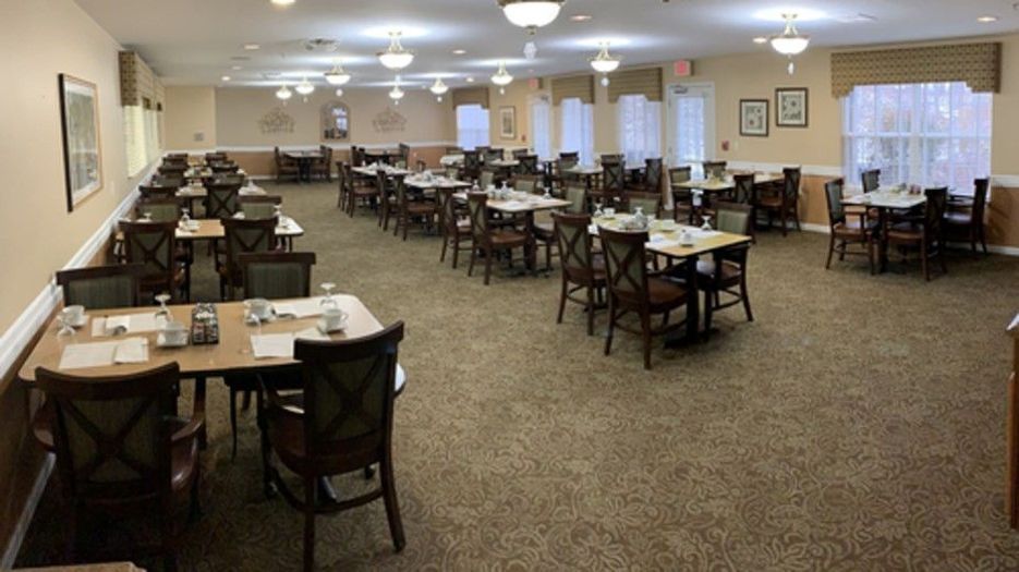 An empty dining room with neatly arranged tables and chairs, softly lit by ceiling lights.