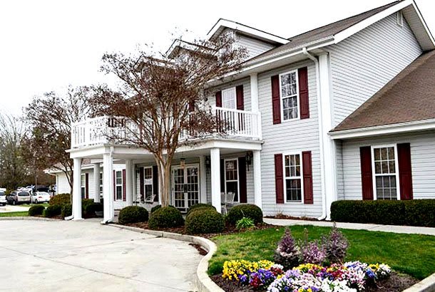 A two-story residential house with a well-maintained garden in the front.