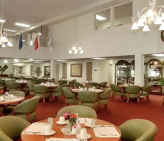 An elegant dining room with neatly arranged tables and chairs, adorned with chandeliers.