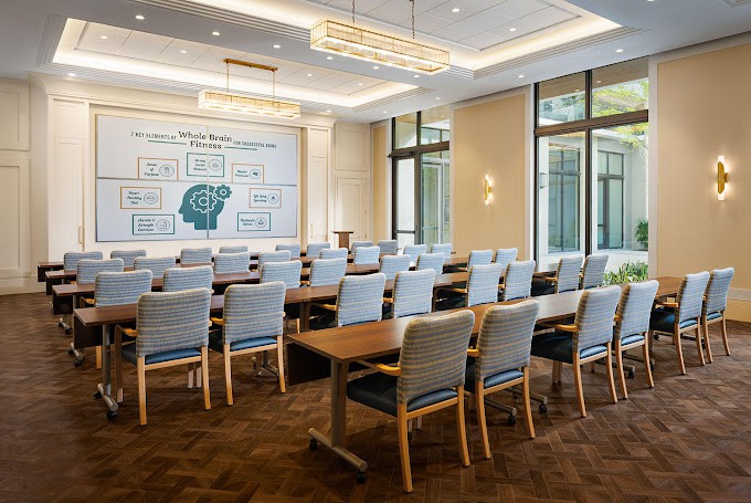 A modern meeting room with a sleek design, featuring multiple chairs and tables arranged for a conference or presentation.