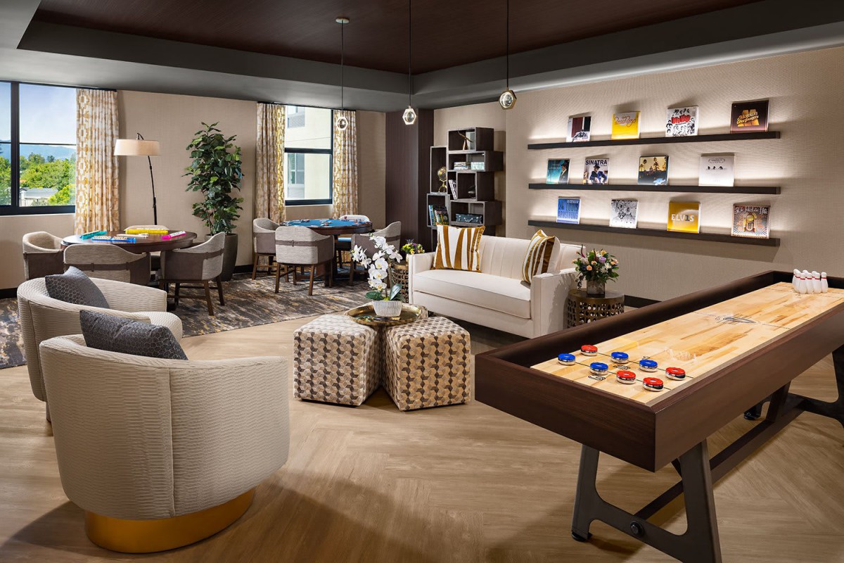 A modern living room with a cozy lounge area, featuring a shuffleboard table and stylish decor.