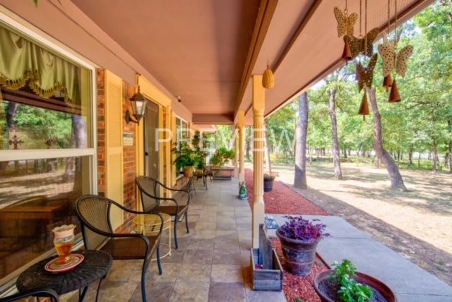A cozy porch with chairs and potted plants overlooking a garden.