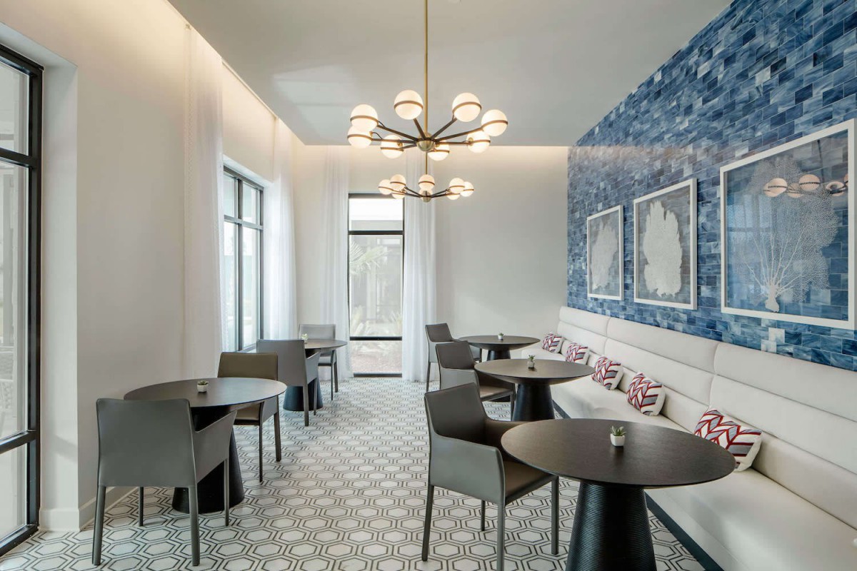 A modern dining area featuring stylish furniture, a unique chandelier, and a vibrant blue accent wall.
