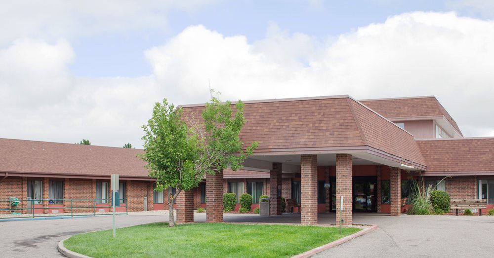 A hotel building with a landscaped entrance and trees.