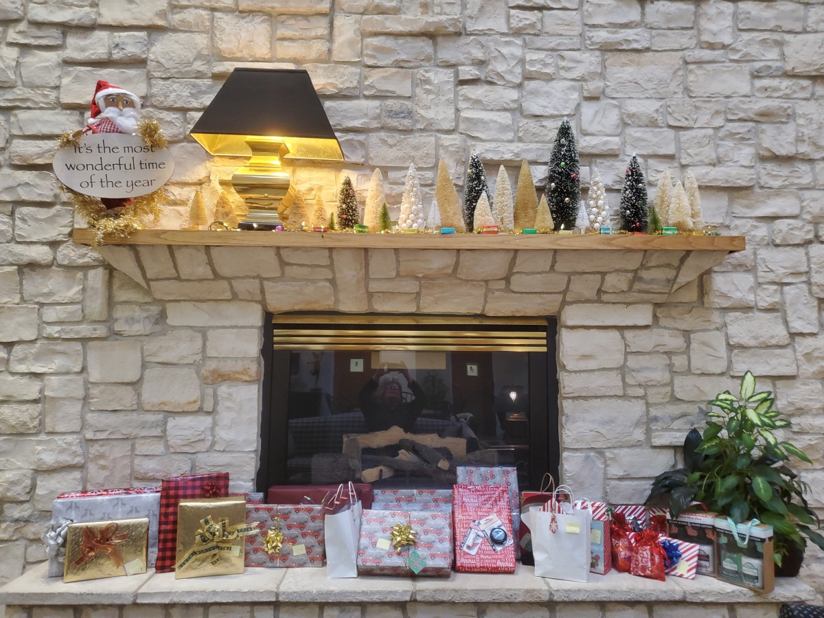 A cozy stone fireplace adorned with Christmas decorations and gifts on the mantel, capturing the holiday spirit.