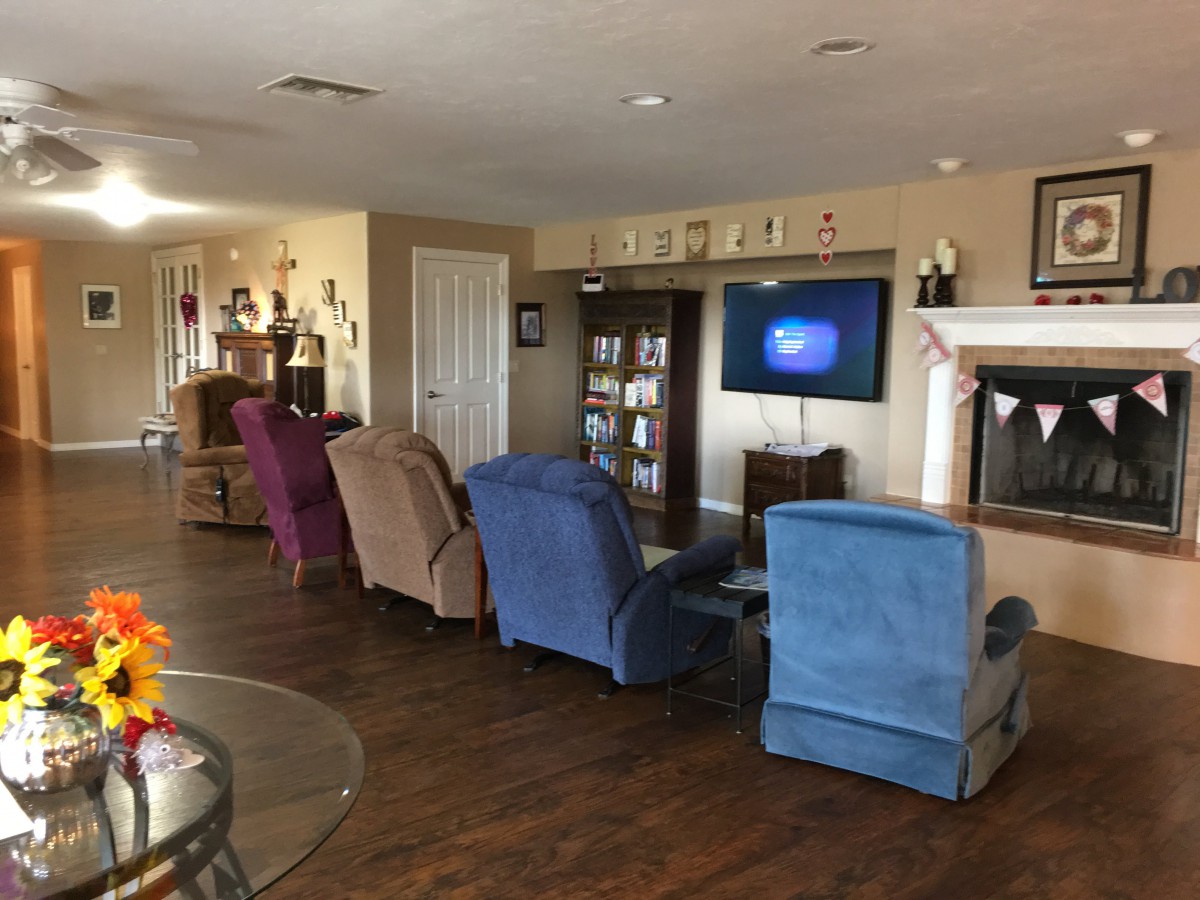 A cozy living room with multiple recliners facing a television and a fireplace.