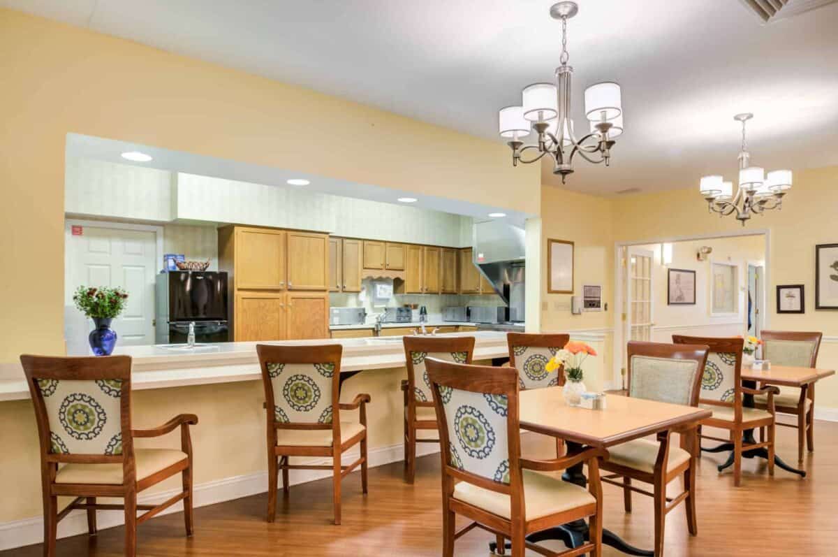 A cozy dining area with wooden chairs and tables adjacent to a kitchen.