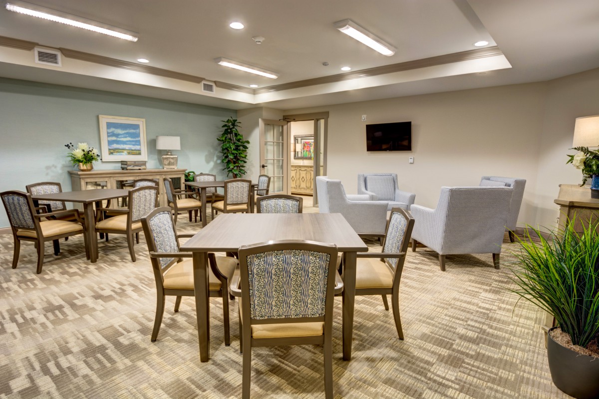 A modern lounge area with tables, chairs, and a television.