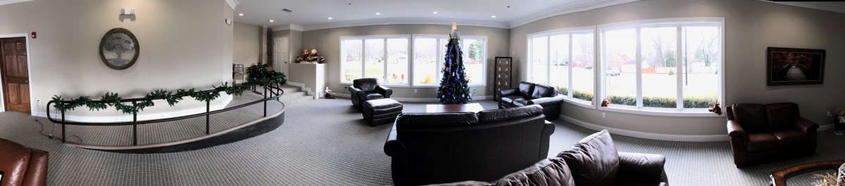 A cozy living room with a Christmas tree and comfortable seating.