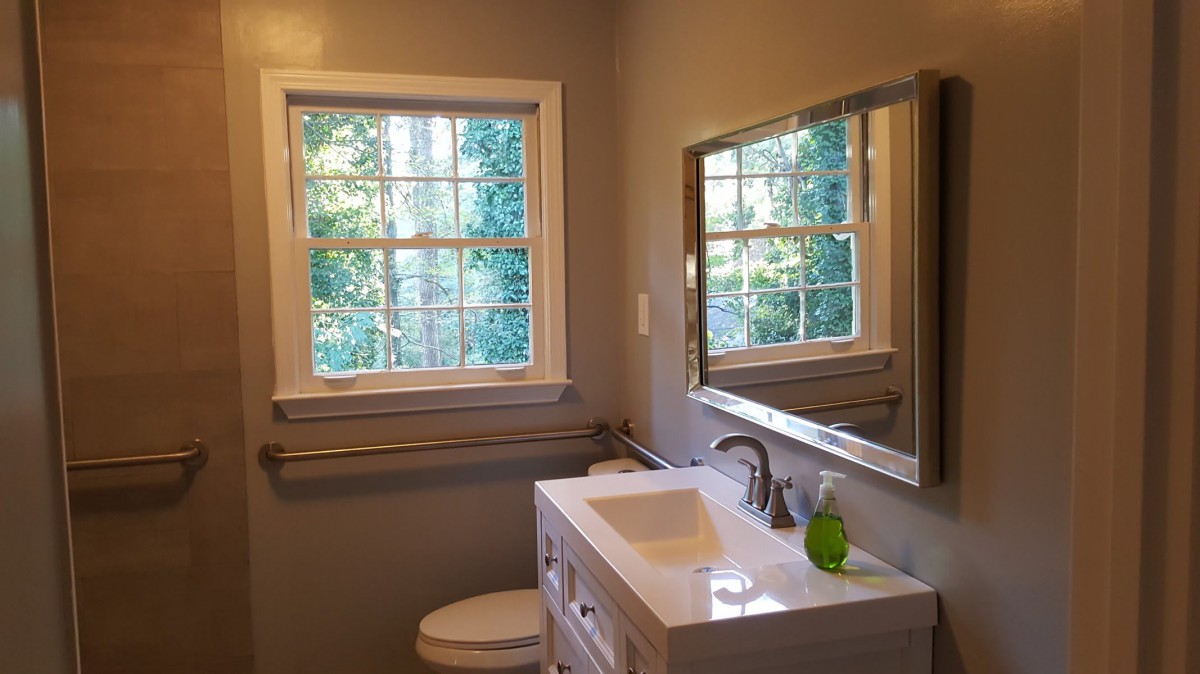 A well-lit bathroom with a large window, modern sink, and mirror.