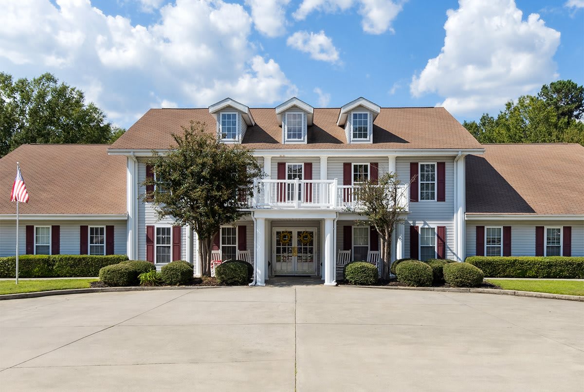 A colonial-style residential house with a spacious front driveway and elegant architecture.