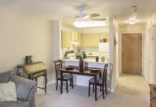 A cozy apartment interior featuring a small dining area with a table and chairs, adjacent to an open kitchen.