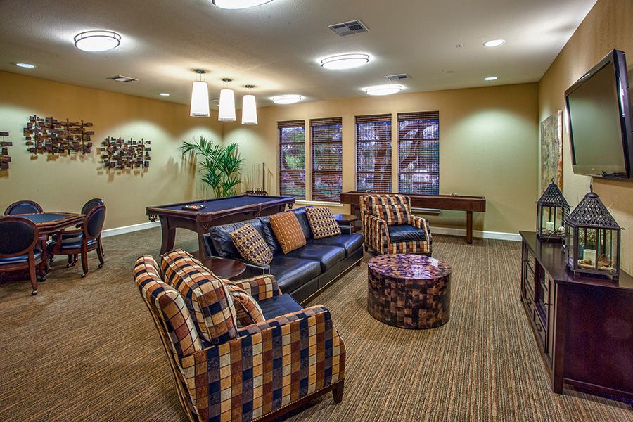 A cozy lounge area featuring comfortable seating and a pool table, with modern lighting and decor.