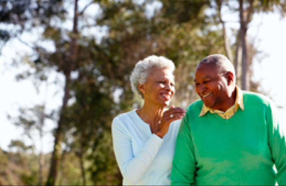 An elderly couple enjoys a cheerful walk outdoors.