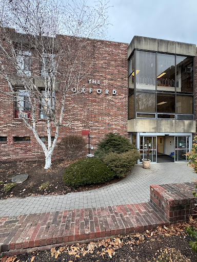 A view of a modern brick building featuring large glass windows and landscaped surroundings.