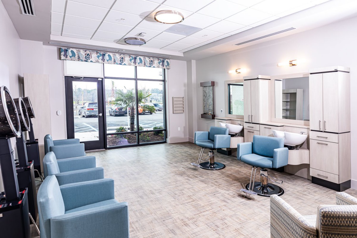 A modern salon interior with blue chairs and large mirrors.