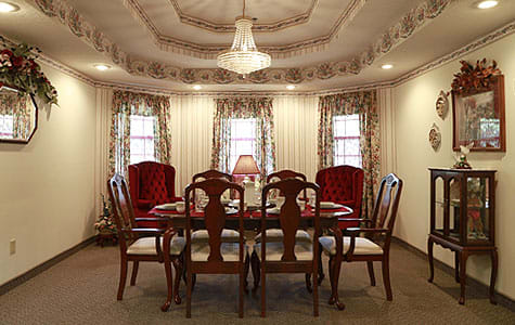 A traditional dining room with a wooden table and upholstered chairs under a chandelier.