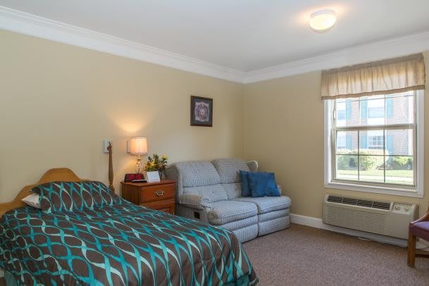 A cozy bedroom with a bed, couch, and warm lighting.