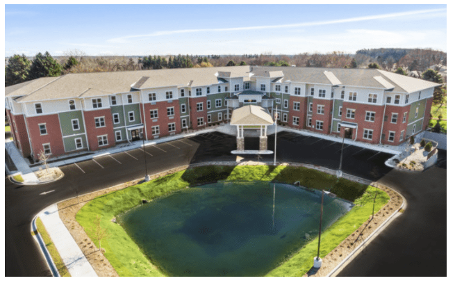 Aerial view of a residential building complex with a central pond.
