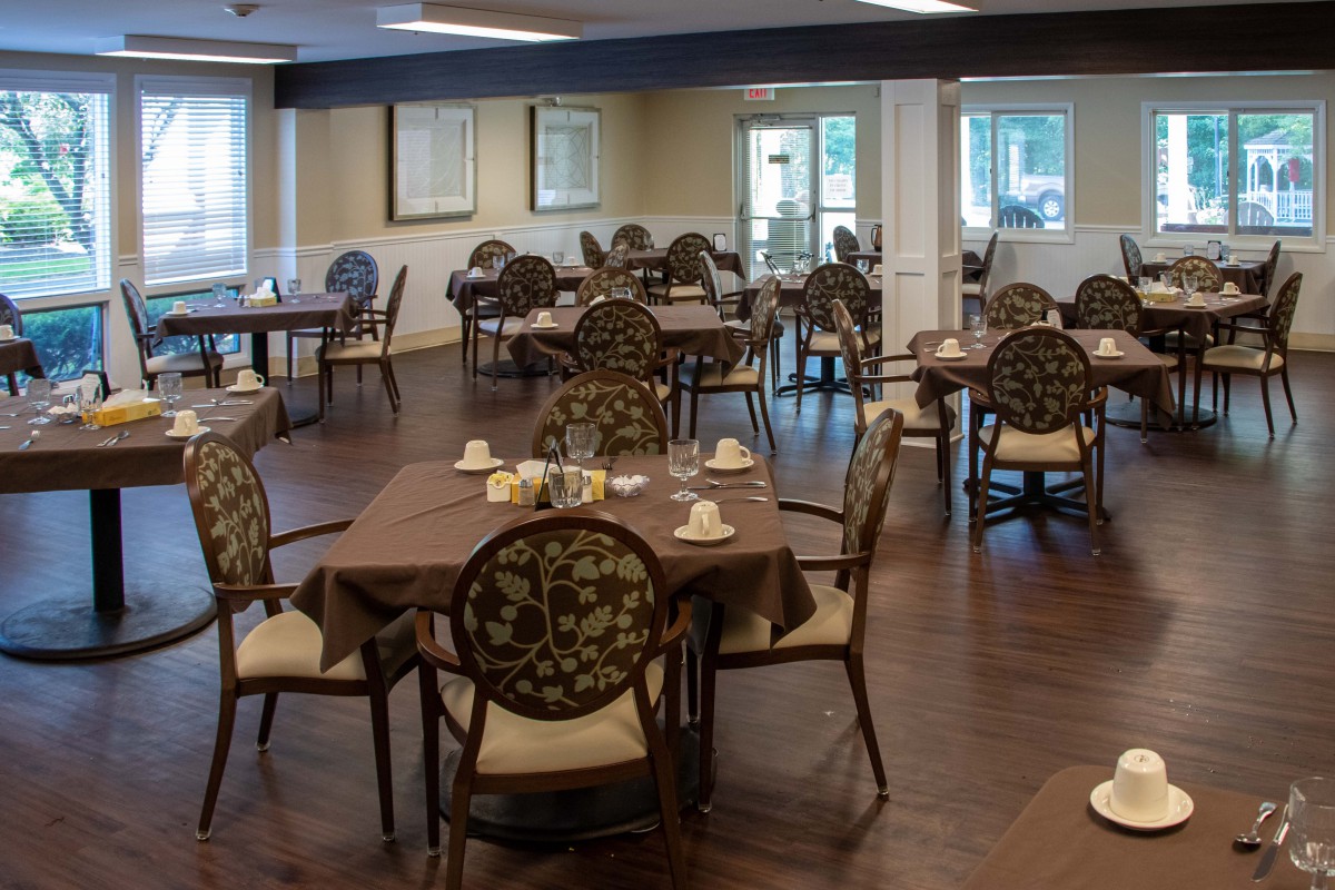An empty dining room with elegantly set tables and chairs.