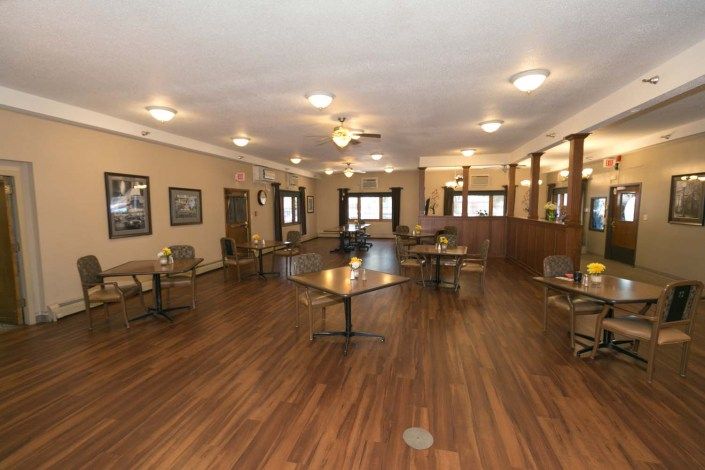 Spacious dining area with wooden flooring and well-arranged tables and chairs.
