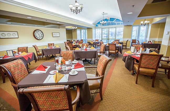 A beautifully set dining room with multiple tables and chairs, featuring elegant tableware and a welcoming atmosphere.