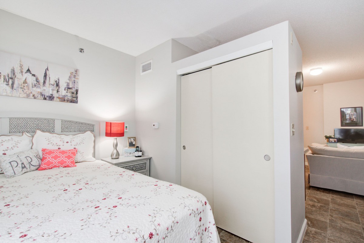 A cozy bedroom with a bed, a side table, and a closet.