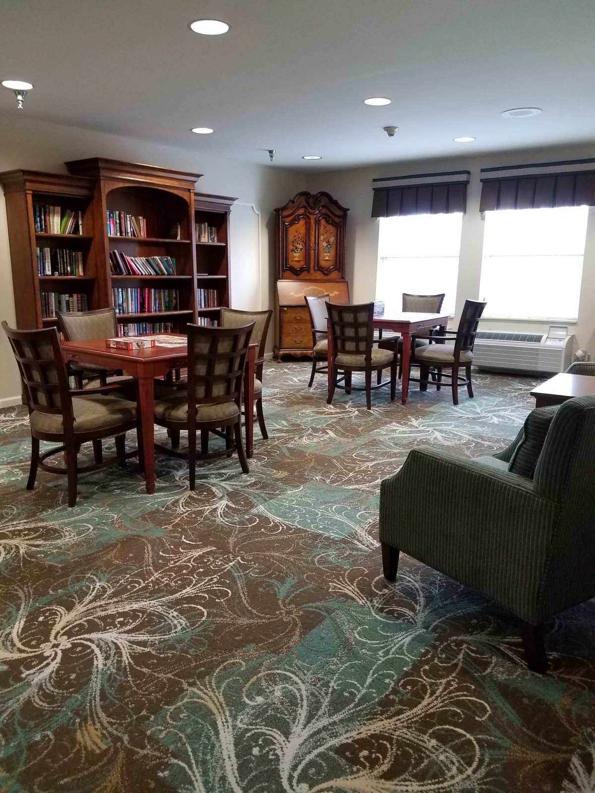A cozy library with bookshelves, tables, and chairs for reading.