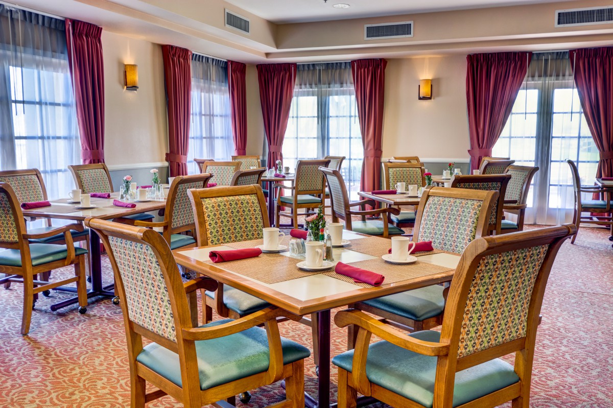A cozy restaurant dining area with neatly arranged tables and chairs, adorned with elegant curtains.