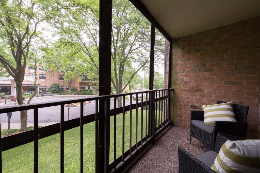A cozy balcony with outdoor seating overlooking a green landscape.