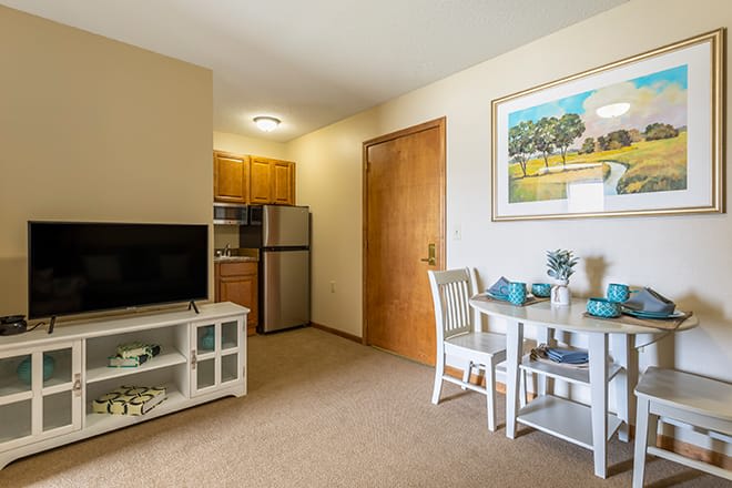 A cozy small apartment with a living area that includes a TV and kitchenette, alongside a compact dining table.