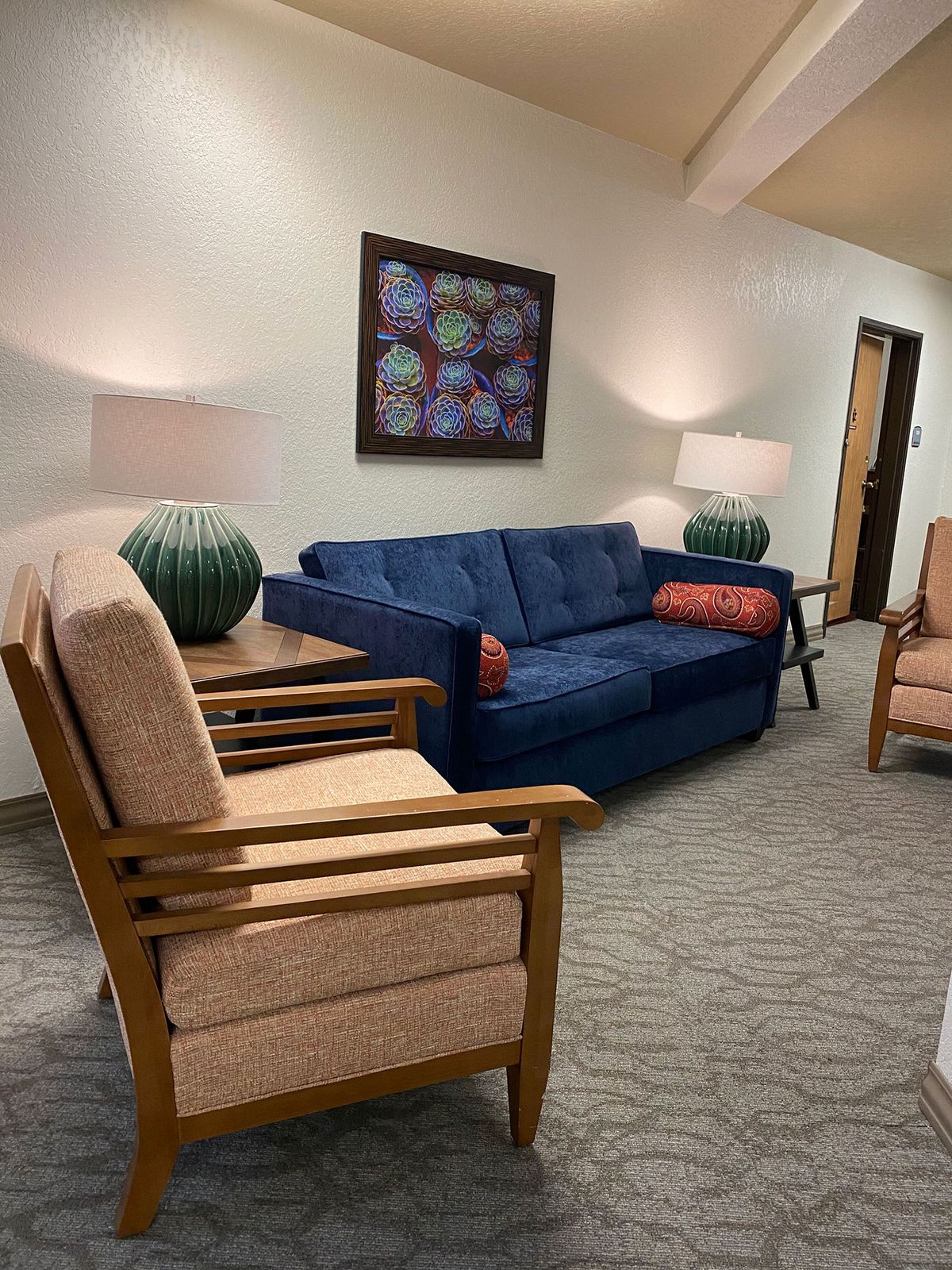 A cozy living room with a blue couch, two armchairs, and decorative table lamps.