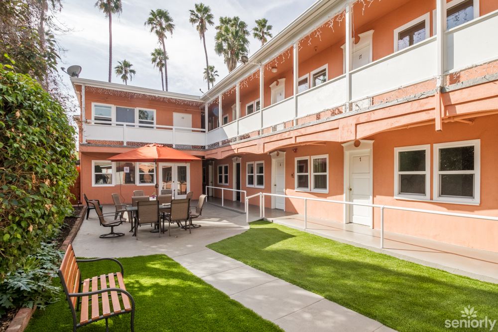 A charming hotel courtyard with outdoor seating and palm trees.